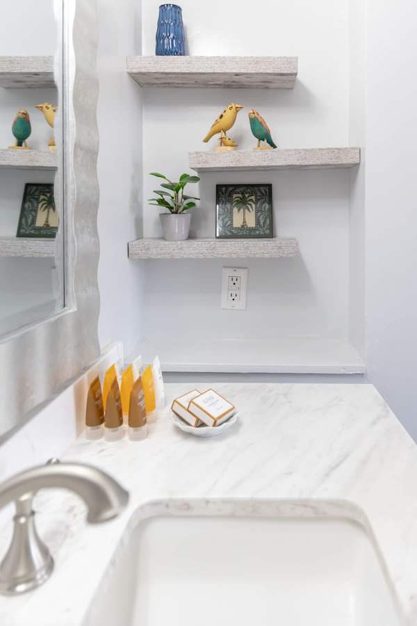 Refresh and recharge in this beautifully appointed bathroom, featuring a marble vanity, starter pack toiletries, and charming decorative shelves for a touch of personalized comfort.