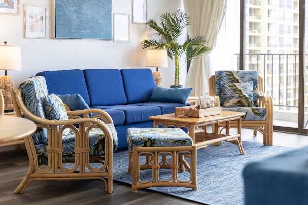 Step into our vibrant and comfortable living room, featuring stylish tropical decor, a blue pull-out sleeper sofa, and direct access to your private balcony for a truly relaxing escape.
