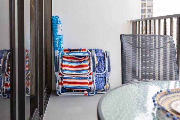 Enhance your beach adventures with the convenience of two vibrant Tommy Bahama beach chairs and a matching umbrella, all readily stored on your private balcony.