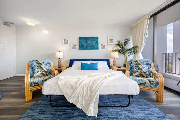 This vibrant living area features a queen-size pull-out sleeper sofa and stylish tropical armchairs, plus direct access to a private balcony for a versatile and enjoyable stay.