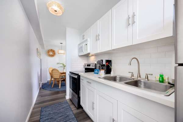 This bright and efficient kitchen features modern white cabinetry, essential appliances, and a convenient layout that flows seamlessly into the inviting dining area.