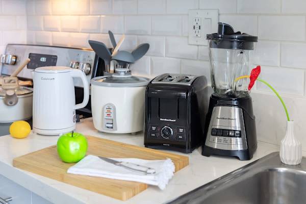 Whip up delicious meals and snacks with ease, thanks to a well-equipped kitchen featuring essential appliances like a Cuisinart electric kettle, rice cooker, Hamilton Beach toaster, and a versatile blender.