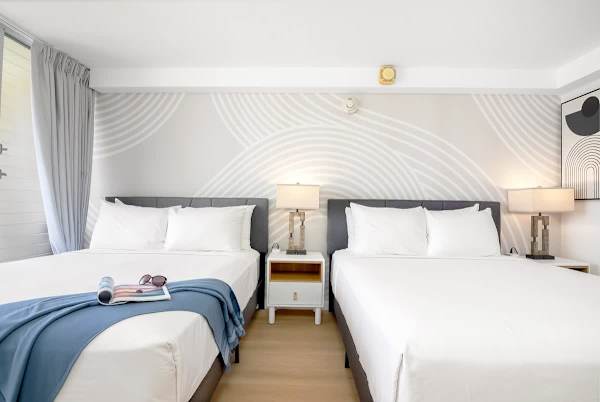 A beautiful studio featuring two comfortable queen beds with clean, fresh linens and modern decor.