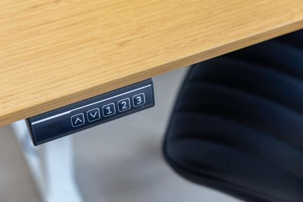 A modern working desk with a built-in control panel for adjusting height.