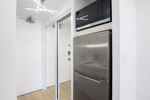 A compact kitchenette featuring a modern stainless steel refrigerator and an over-the-range microwave.