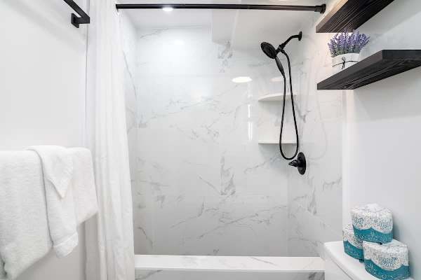 A pristine and stylish shower with a sleek black shower head and white marble-patterned walls.