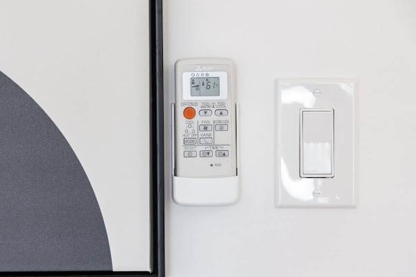 A mounted remote control for the air conditioner, allowing for easy climate control.