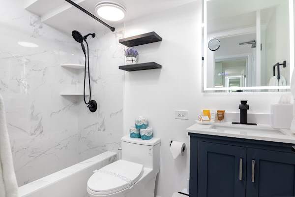 Modern and stylish bathroom featuring sleek black fixtures, marble-tiled shower, and elegant vanity with ample lighting.