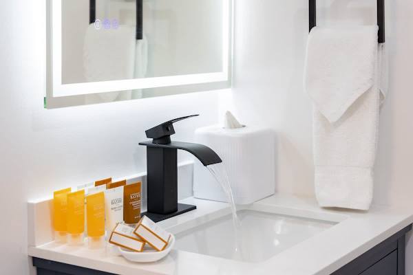 A modern bathroom sink and faucet, with complimentary toiletries provided for guests.