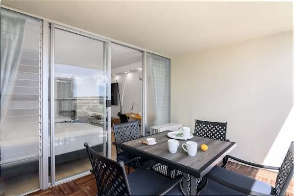 A balcony with an outdoor dining table and chairs, offering a bright and inviting space to relax.