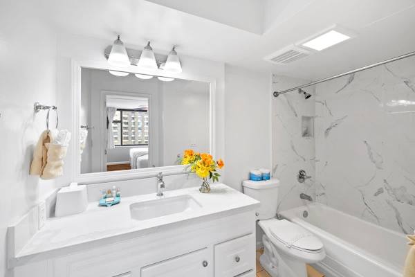 Refresh in the sparkling clean bathroom featuring a modern marble-style shower/tub combo and a bright vanity with ample counter space.
