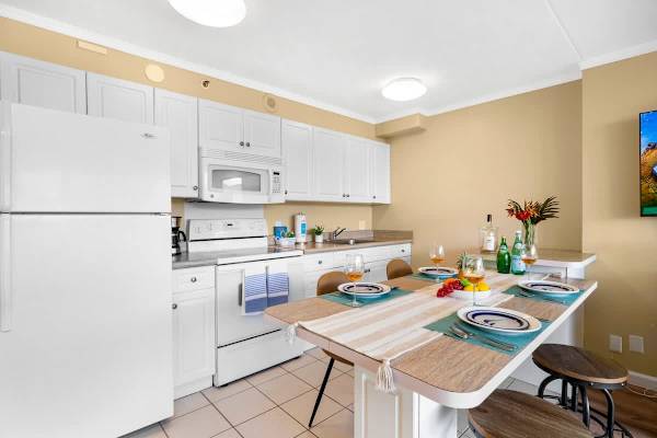 Prepare meals easily in this full kitchen featuring clean white cabinets and appliances, paired with a convenient dining table.