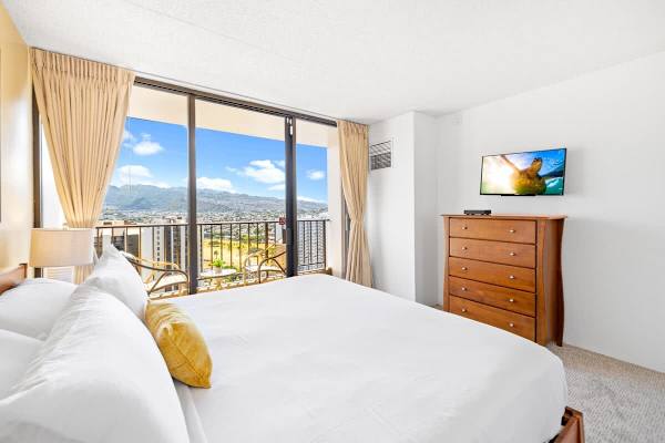 Relax in your bedroom featuring a King bed, a mounted TV, and sliding glass doors leading to the balcony with phenomenal mountain views.