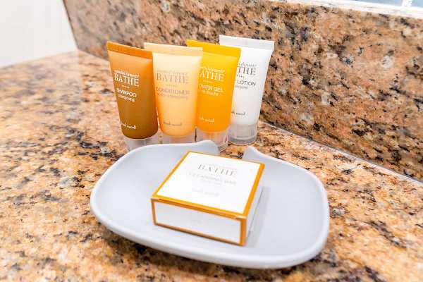 Enjoy the convenience of complimentary bath amenities, including shampoo, conditioner, shower gel, lotion, and soap, provided on the granite countertop.