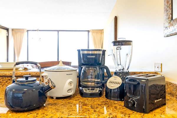 The kitchen is fully equipped with essential small appliances, including a coffee maker, toaster, blender, rice cooker, and kettle, all set on a granite countertop.