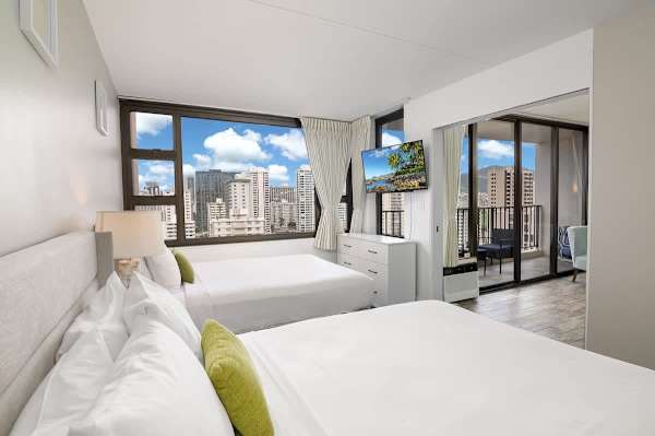 This bright and spacious bedroom features 2 Queen beds, a 40" Smart TV, and glass windows that offer dynamic city views.