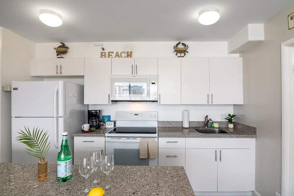 Prepare your vacation refreshments in this clean, well-equipped kitchen featuring modern white cabinets, appliances, and cute decors.