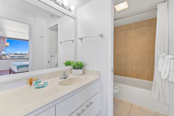 Bright bathroom with a large mirror and tiled bathtub area