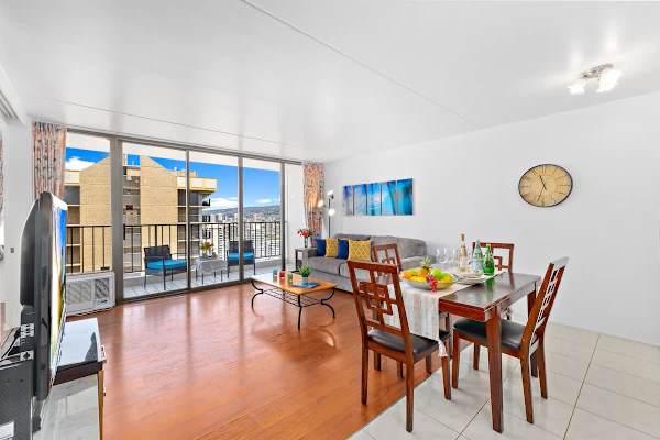 Bright living and dining area with balcony seating and city views.