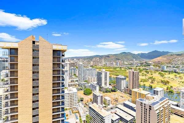 Cityscape view from a high-rise building with mountains in the background.