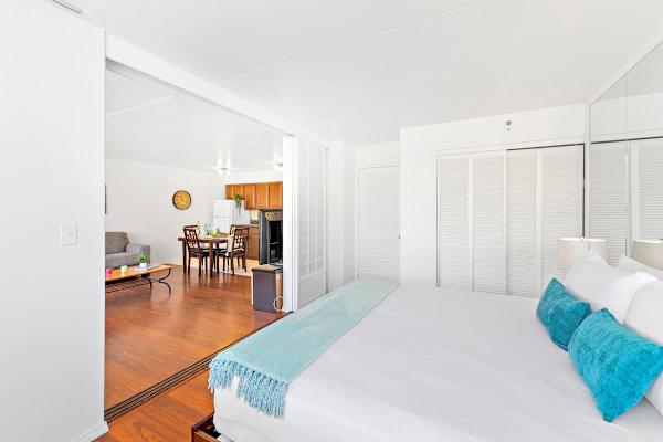 Bright bedroom with sliding doors opening to a spacious living and dining area
