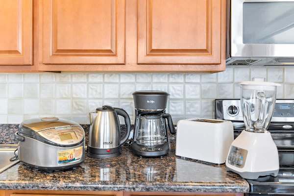 Kitchen countertop with modern appliances including a rice cooker, electric kettle, coffee maker, toaster, and blender.