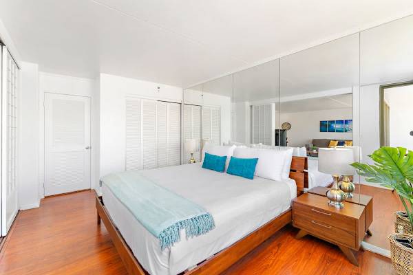 Bright bedroom with wood flooring and mirrored wall creating a spacious feel.
