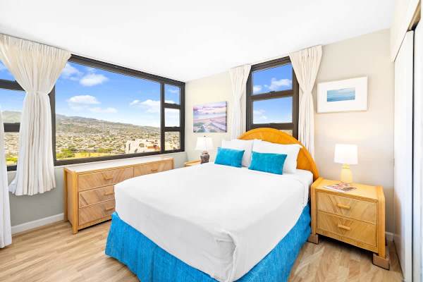 Your bedroom features a Queen bed, rattan furnishings, and large windows offering spectacular elevated views of the mountains and city.