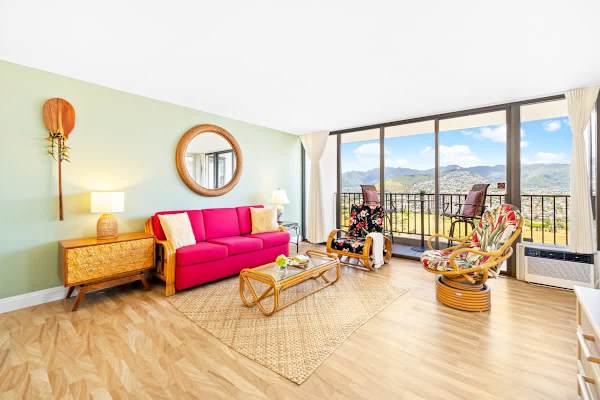 Relax in this bright and cheerfully decorated living room featuring a pull-out sleeper sofa, tropical rattan furnishings, and stunning mountain views from the full wall of windows.