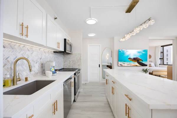 Cook with a view in this stunning, fully-equipped kitchen featuring marble-style countertops, gold accents, and a sleek herringbone backsplash.