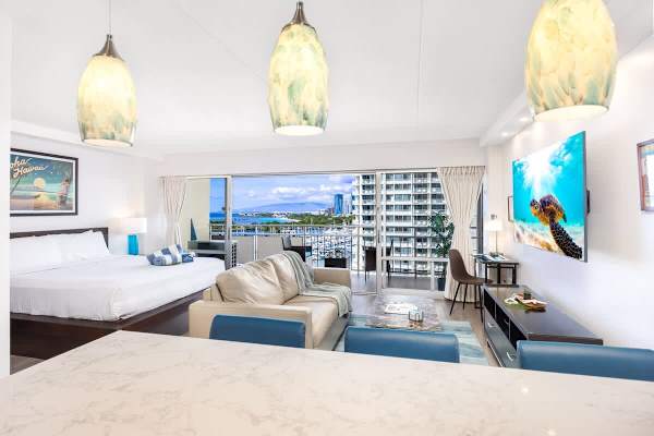 Cozy studio apartment with a plush king bed, pull-out sleeper sofa, and a stunning private balcony view of the harbor and cityscape.