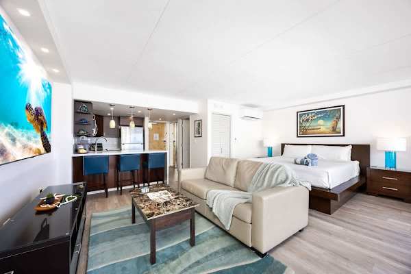 Relax in your modern studio featuring a king-size bed, a kitchen with bar seating, a sleeper sofa, and a 65" Smart TV.