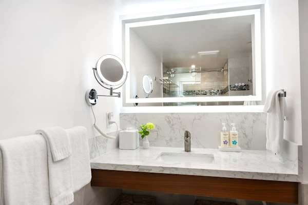 Your bathroom vanity area features a white marble countertop and backsplash, a vessel sink, and a large backlit mirror for ample illumination.