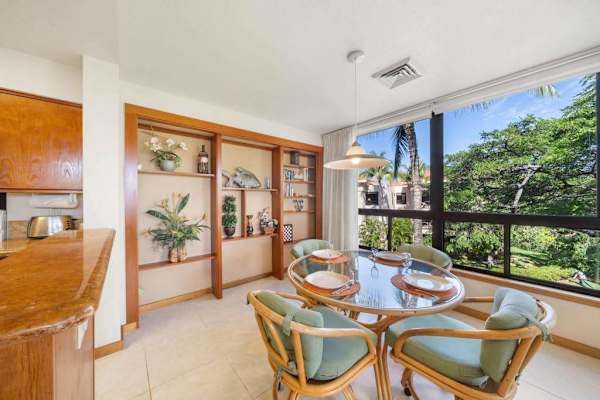 Dining area pairs table, colorful chairs, artwork, and garden views