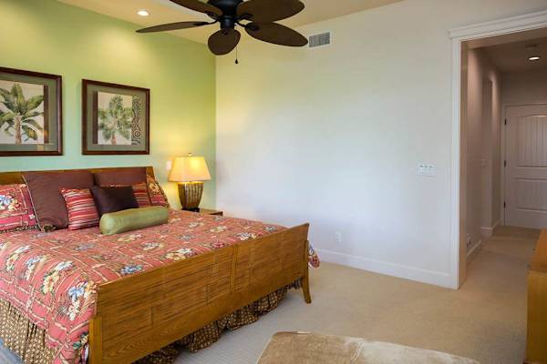 Spacious Primary Suite Bed Area with Tropical Decor & Ceiling Fan