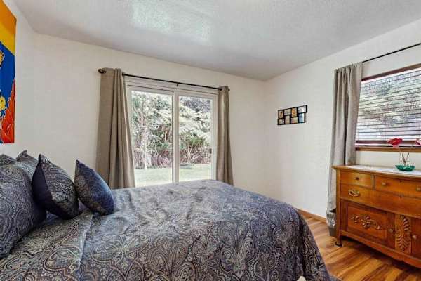 Guest Bedroom with Patterned Bedding, Wooden Dresser & Patio Door