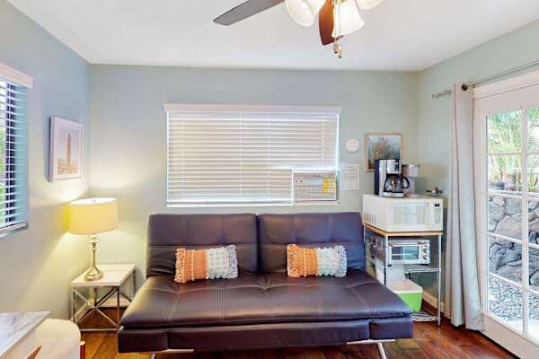 Cozy secondary living room equipped with a convertible sofa, cooling ceiling fan, and a convenient coffee and microwave station! 🛋️✨