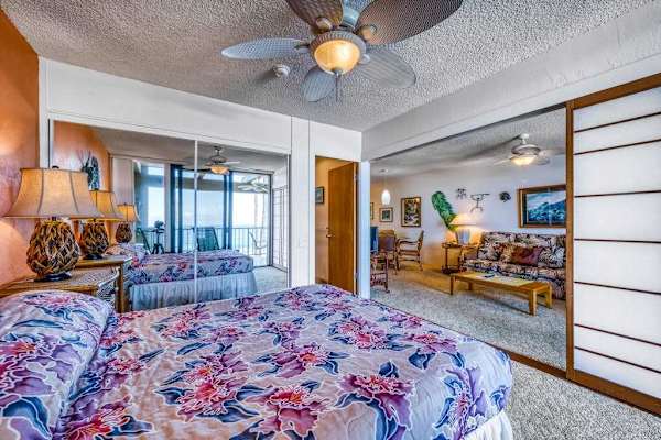 Comfortable bedroom setup featuring a cozy bed, ceiling fan, and full-length mirrored closets
