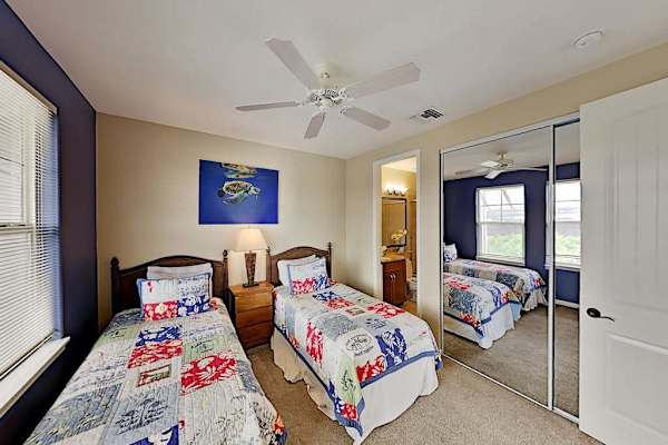 Guest bedroom with two twin beds, flat screen tv and an en-suite bathroom.