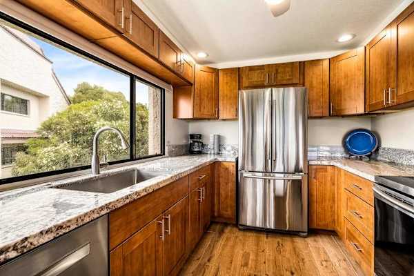 A bright kitchen workspace featuring a deep sink situated right under a large window with outdoor views