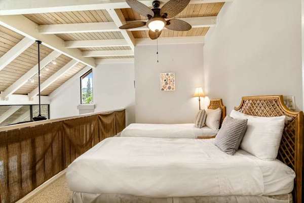 A cozy loft bedroom featuring two comfortable beds and a beautiful vaulted wooden ceiling