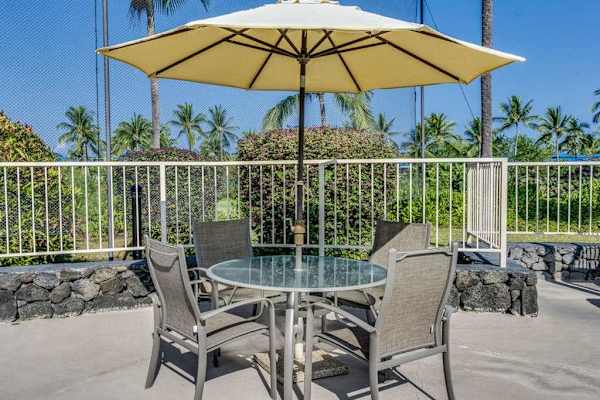 Relax by the pool deck at the outdoor dining table, complete with a large sun umbrella