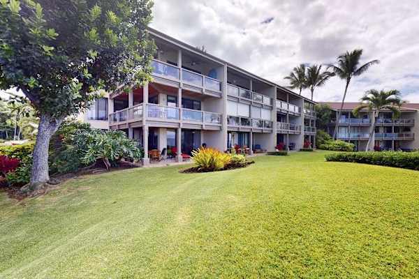 Resort Exterior View Featuring Manicured Green Lawn, Private Balconies, and Tropical Trees