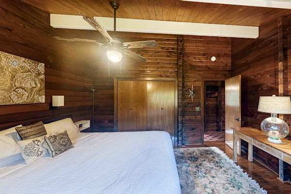 Guest bedroom with a queen bed, ceiling fan and lots of natural light. 