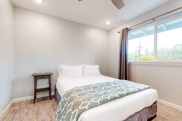 Guest room with queen bed and large windows. 