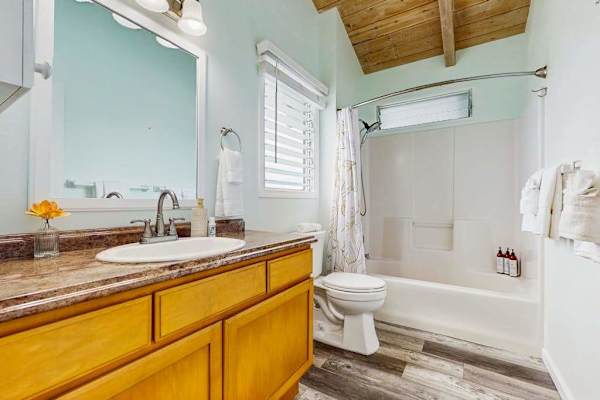 Full bathroom features vanity shower mirror and clean tiled finishes