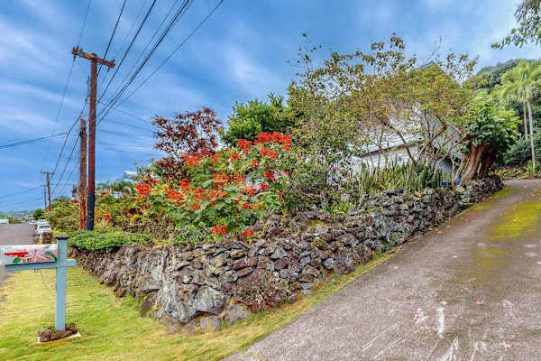 Exterior pathway winds beside landscaped grounds and neighborhood greenery nearby