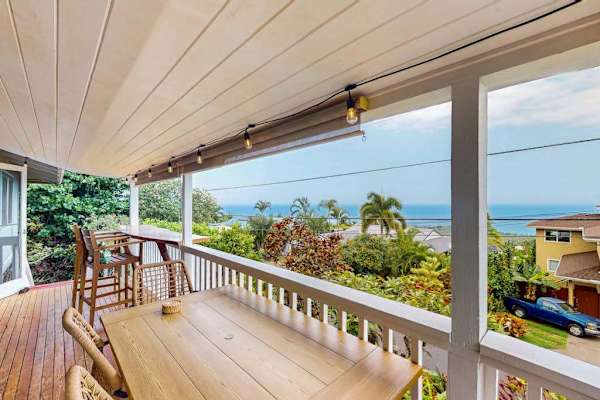 Covered balcony frames island scenery with outdoor seating and sunshine