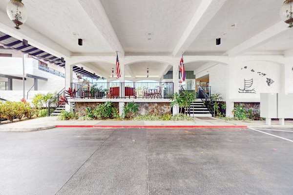 Covered entrance welcomes guests with open seating and tropical surroundings