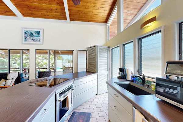 Bright kitchen features island seating appliances and garden-facing windows nearby